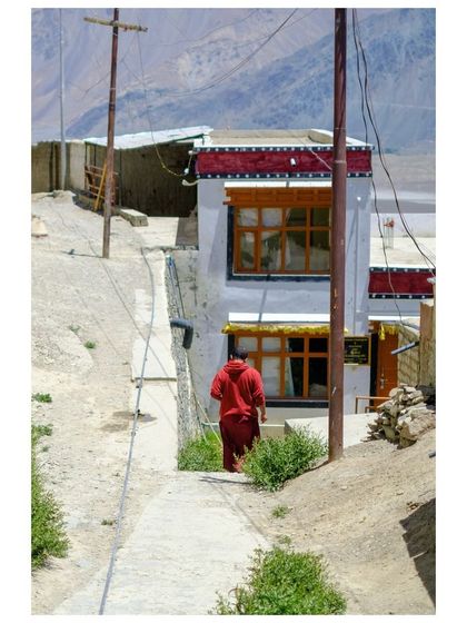 A monk walks down a narrow path, a slice of daily life in a Ladakhi village.