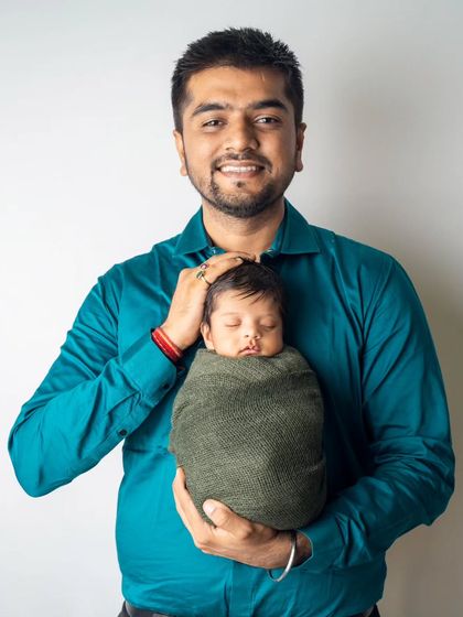 A proud father holds his sleeping baby, a perfect little bundle. We love capturing these early moments of fatherhood.