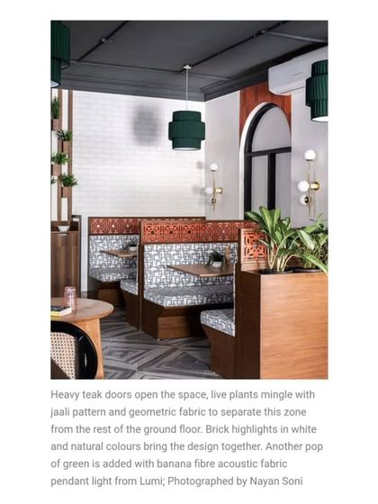 This featured shot shows how heavy teak doors open into this intimate zone. Live plants, geometric fabrics, and brick highlights create a space that feels distinct yet connected to the rest of the restaurant.