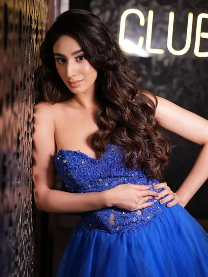 A full-length shot showing the complete cocktail look. The soft makeup allows the stunning blue gown to be the star of the show.