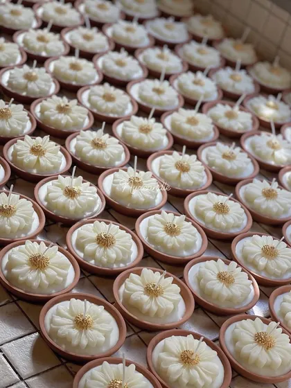 A large batch of our earth pot daisy candles, ready for packaging. These charming candles combine a rustic terracotta base with a delicate floral design, making them a popular choice for festive favors.