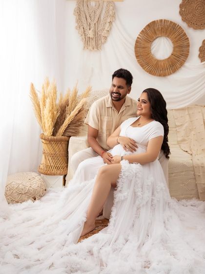 A sweet moment between partners in the boho setting. Their coordinated neutral outfits complement the natural, earthy tones of the setup perfectly.