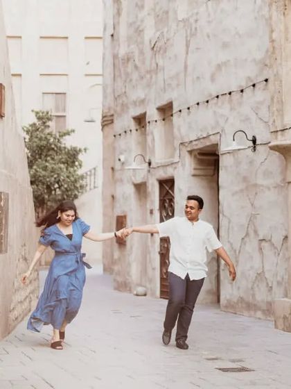 A happy, energetic shot of a couple running through the old alleyways of Dubai. This image tells a story of adventure and shared excitement in a unique urban setting.