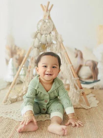 Cuteness overload. This happy one-year-old is all smiles during his birthday photoshoot, sitting in front of a fun teepee setup in the studio.