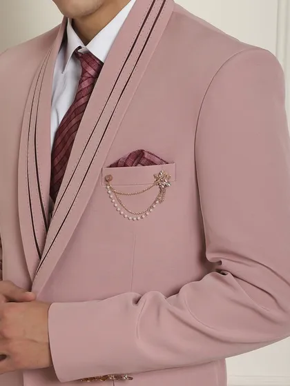 A close-up of the pink suit, showing the lapel pin and chain accessory. These small details add a layer of sophistication.