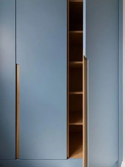A detail shot of a wardrobe in a calming blue matte PU finish. The integrated CNC handle is crafted from wood, providing a beautiful contrast and a touch of warmth.
