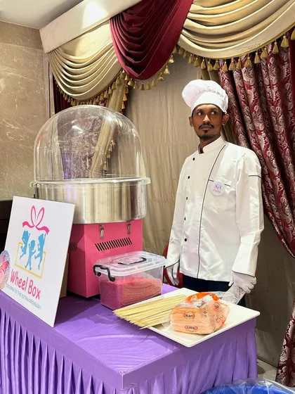 Our professional staff member ready to serve at an event. He stands beside the cotton candy machine, prepared with sticks and sugar for a sweet celebration.