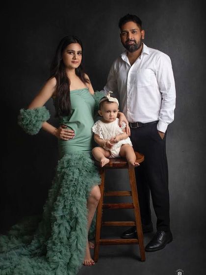 A stylish and classic family portrait. The mother's dramatic green gown adds a touch of glamour to this elegant photo against a dark backdrop.