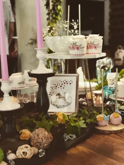 A wider view of the dessert table, showing how we layer different heights and elements. From tall candles to low-lying greenery and multi-tiered stands, the composition is designed to be visually dynamic and inviting.