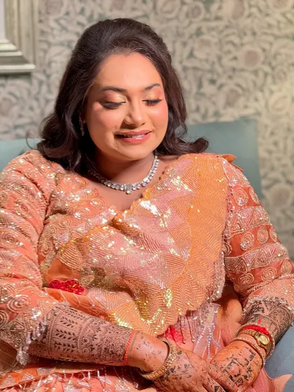 A soft and romantic Sangeet look. The makeup features peachy tones on the eyes and cheeks, paired with a simple diamond necklace.