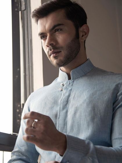 A light blue linen shirt with a mandarin collar and unique button details. This piece blends comfort and elegance, perfect for summer.