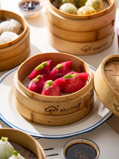 Vibrant pink dumplings in a steamer basket. The bright color is unexpected and immediately grabs your attention.