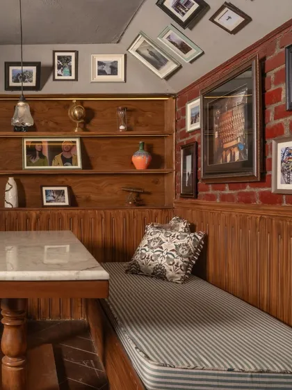 A cozy booth seating area at Echoes, with a marble-topped table, wood-paneled walls, and a collection of framed pictures. The design creates a warm, intimate nook perfect for conversation.