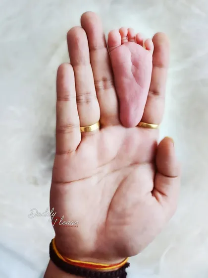 A powerful image showing just how small your newborn is, with their tiny foot resting in the palm of a parent's hand. This shot emphasizes the delicate size of your new baby.