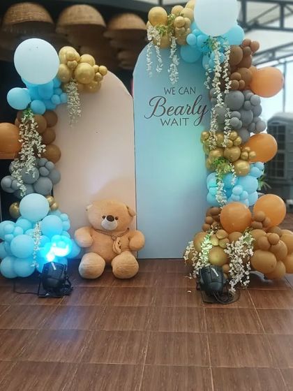 A fun 'We Can Bearly Wait' teddy bear themed decoration. This outdoor setup uses a rustic color palette of brown, blue, and grey balloons, perfect for a modern baby shower.