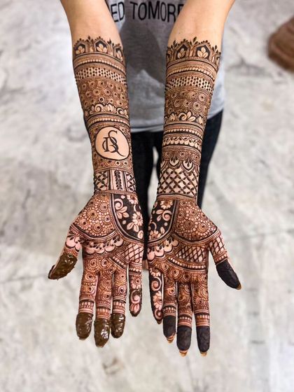 This bridal design combines traditional patterns with a personalized touch. A custom monogram with the couple's initials, D and S, is featured prominently on the forearm.