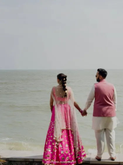 A quiet, romantic moment as the couple holds hands and looks out at the sea during their beach wedding in Thailand.
