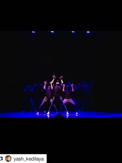 My crew takes the stage under dramatic blue lighting, hitting a powerful pose in unison. This shot from a live performance highlights the synchronization and stage presence we build in our classes.