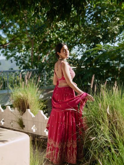 Another angle of the pink lehenga, capturing a soft, elegant pose amidst nature. This look is ideal for daytime functions and pre-wedding shoots.