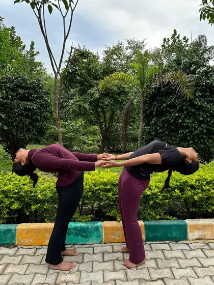 A partner backbend, holding hands for support. This pose helps build trust and allows for a deeper stretch than one could achieve alone.
