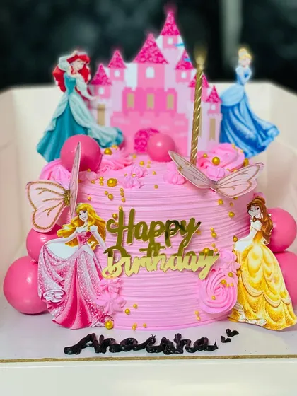 A fairytale princess cake featuring multiple Disney princesses and a castle topper.