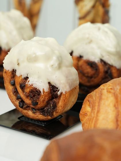 A delicious-looking cinnamon roll with cream cheese frosting, made with an enriched dough. This is one of the many popular items covered in our bread and pastry modules.