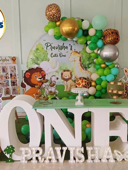 A "Cute One" jungle theme for a first birthday. This setup features a large 'ONE' table, animal cutouts, and a green and silver balloon arch.