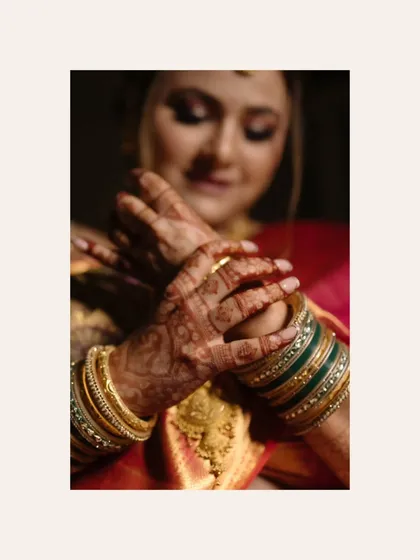 A close-up of the bride's hands, adorned with intricate mehendi and beautiful green and gold bangles. This shot captures the rich traditions and colors of her bridal look.