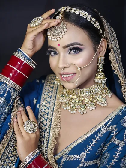 A smiling bride in a royal blue outfit. The makeup is designed to make her eyes pop, with a flawless base that enhances her natural features.