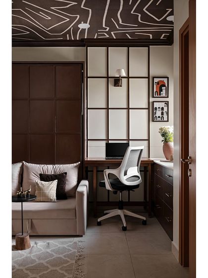 The studio room embraces a richer, moodier vibe with deep chocolate brown walls and ivory accents. The true conversation starter is the abstract wallpaper on the ceiling, an unexpected twist that makes the room stand out.