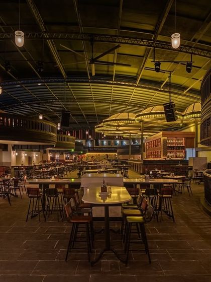 A look at the different levels and seating areas, showing how the space can feel both vast and intimate. The dark wood balconies and exposed ceiling structure are key material choices.