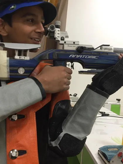 A close-up of a young rifle shooter with his Anatomic rifle, smiling after a good session. This is the future.