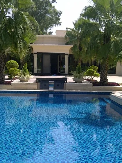 A clean, modern poolside we executed for a client, transforming their backyard into a luxurious retreat. The design features pristine blue mosaic tiles, manicured topiary, and elegant palm trees, reflecting a perfect balance between architectural structure and natural elements.