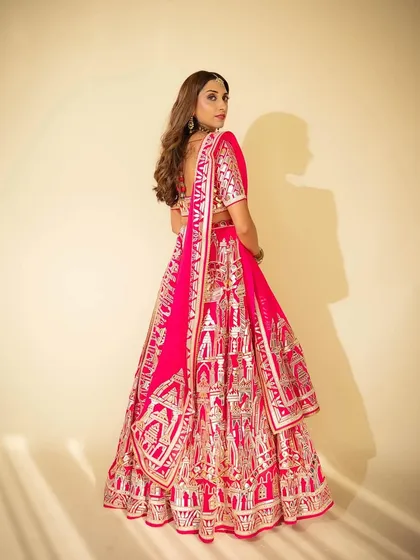 A stunning Mehendi look for the sister-in-law of the groom. The makeup is glamorous yet appropriate for a daytime event, with a focus on defined eyes and a bold pink lip to match her beautiful lehenga.