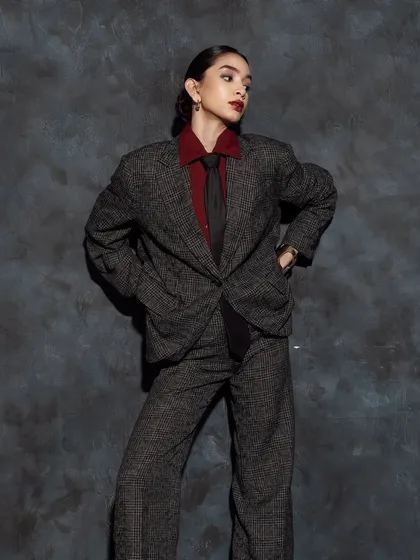 The androgynous styling is complemented by a strong yet clean makeup look, focusing on flawless skin and a statement lip.