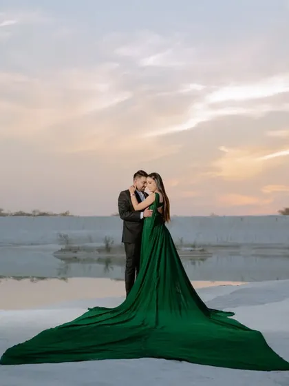 A full-length shot showcasing the couple and the stunning green trail gown against the vast, white landscape. This is the kind of "wow" shot that belongs on a large canvas.
