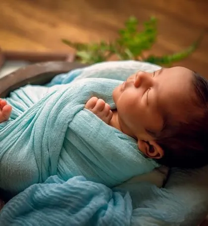 A simple and elegant wrap in a soft blue fabric. This pose highlights the baby's tiny hands and peaceful sleeping face, all while keeping them securely swaddled.
