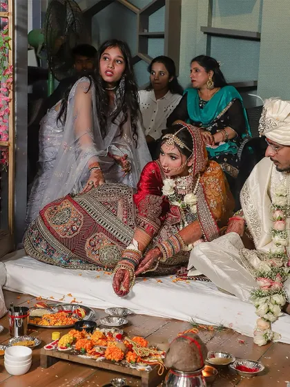A wide shot of the wedding mandap during the pheras. This image shows the bride and groom surrounded by their family, capturing the full context and atmosphere of the traditional ceremony.