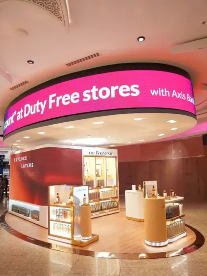 This photo captures a beauty brand's pop-up within the duty-free area, complete with a large curved LED screen. We document how brands integrate digital and physical advertising in a retail environment.