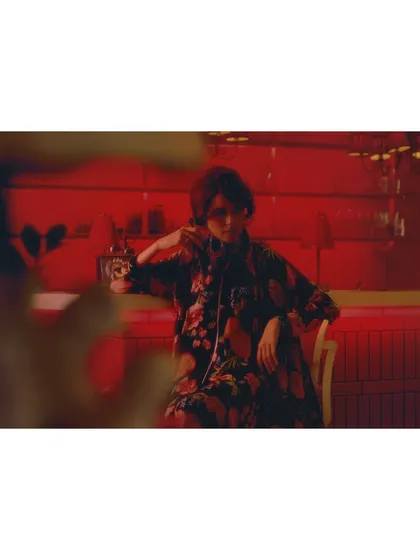 The heroine waits by a vintage phone in a room saturated with red light. The styling and setting are heavily influenced by Wong Kar Wai's 'In the Mood for Love', creating a palpable sense of anticipation and longing.