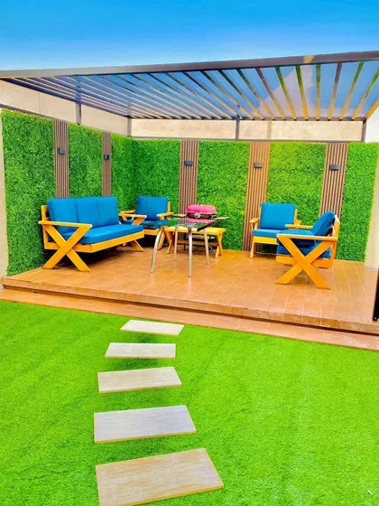 Imagine your terrace as the perfect spot for a sunny weekend brunch. We created this vibrant outdoor lounge with comfortable seating, durable artificial turf, and a signature green wall accented with wood panels, all under a modern pergola.