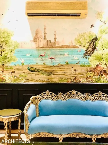 The full view of the feature wall, where a scenic wallpaper depicting a lakeside view with peacocks creates a sense of depth and artistry behind the classic blue sofa.