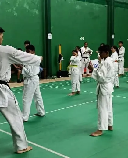 A senior black-belt student demonstrates the correct form for younger students during a belt grading exam.