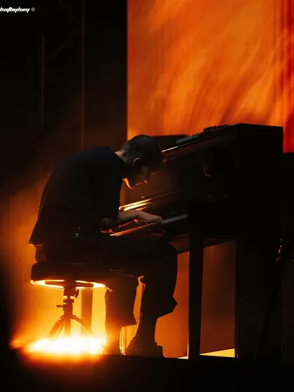 Ben Böhmer in a moment of quiet intensity, focused on his keyboard during his live set in Bangalore. The warm, focused lighting creates an intimate portrait amidst the large-scale production, showing a different side of live performance.