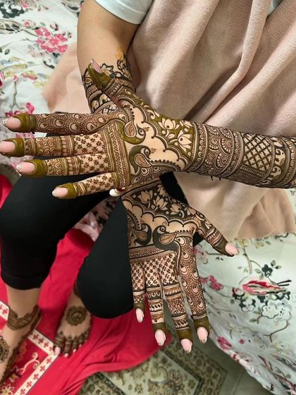 A clear shot of a coordinated bridal set. The hands feature peacock designs, while the feet have matching patterns, demonstrating a complete and elegant package.