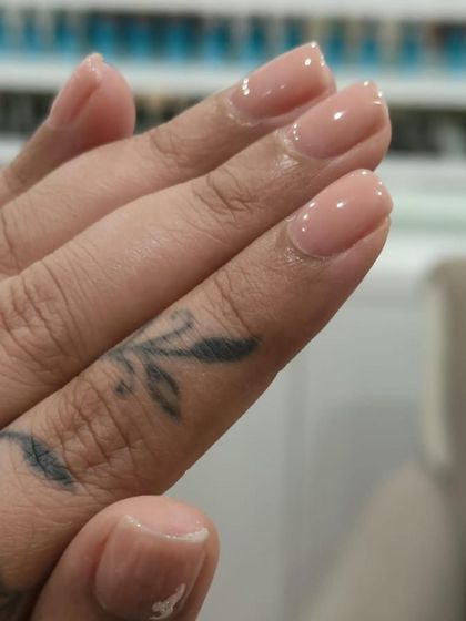 A close-up of a delicate and clean gel manicure. The rosy-nude shade gives the nails a healthy glow, perfect for a natural and polished everyday look.