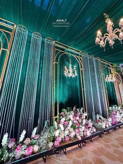A look down the walkway, lined with floral arrangements and framed by gold arches and crystal curtains.