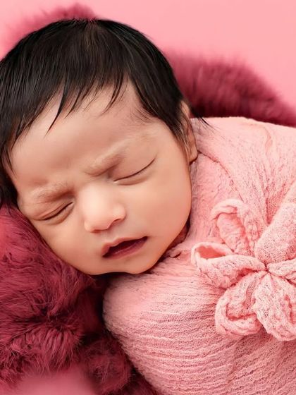 A close-up on the baby's face, showing the texture of the pink wrap and their peaceful expression.