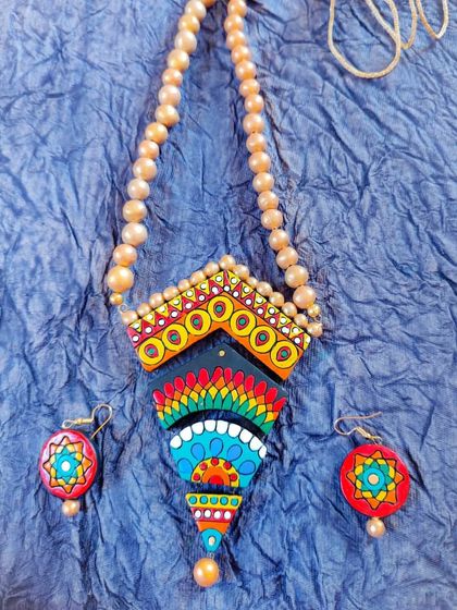 This geometric, multi-colored terracotta necklace has a unique, tapered pendant. The vibrant colors and artistic design make it a true statement piece.