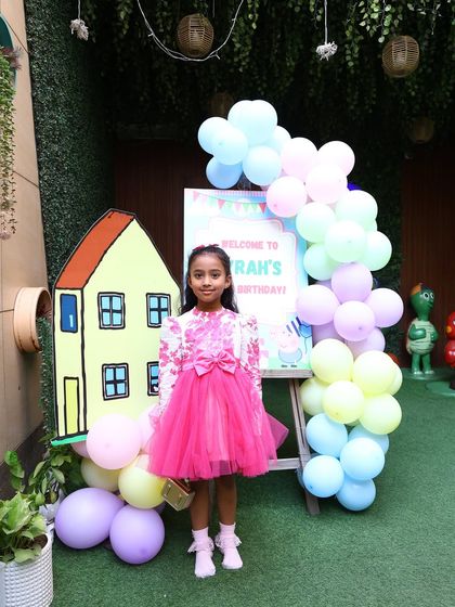 The birthday girl stands by her personalized welcome sign, ready to greet her guests for an oink-tastic celebration.